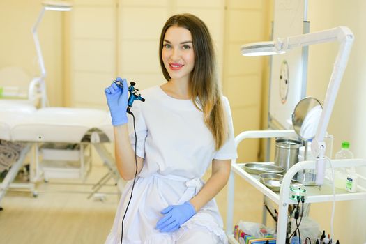 Young permanent makeup artist sitting with microblading device at beauty salon. Concept of cosmetology equipment and cosmetologist with modern technology.