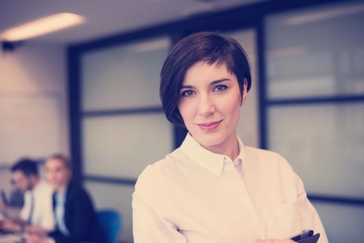 young hispanic businesswoman portrait with  tablet computer at modern startup business office interior, people group on team meeting blured in background