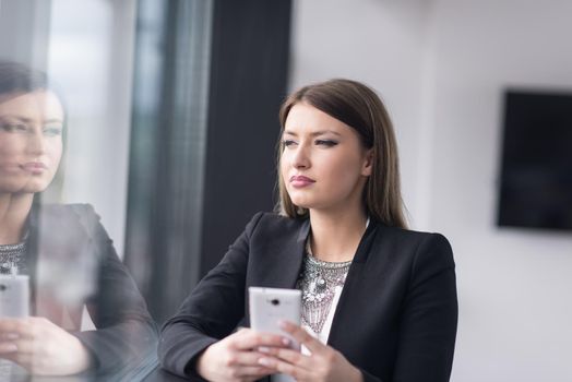 businesswoman speeking on phone beside window of modern office