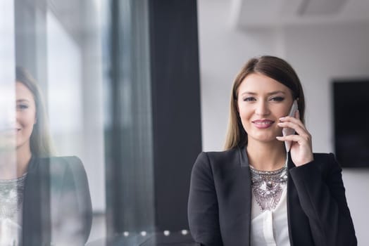 businesswoman speeking on phone beside window of modern office