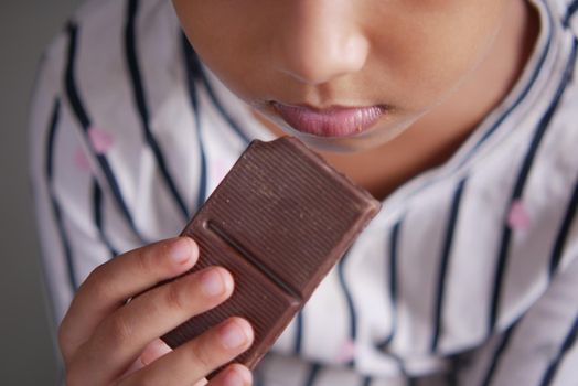 child girl hand pick dark chocolate against gray background ,
