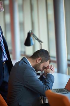 Frustrated young business man have stress problems. Sitting alone at office meeting room  and working on laptop compute.