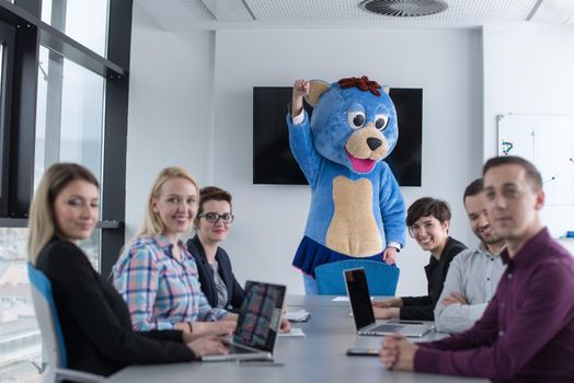 Boss dresed as teddy bear having fun with bussines people in modern corporate office