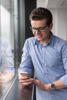 businessman using a phone beside window of modern office