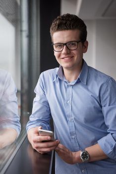 businessman using a phone beside window of modern office