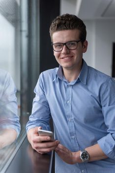 businessman using a phone beside window of modern office