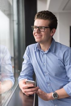 businessman using a phone beside window of modern office