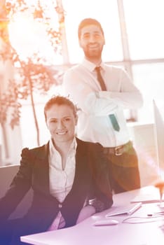 business couple working together on project at modern startup office. Early morning scene with sun flare in background