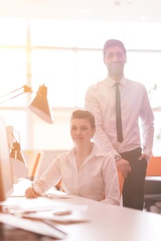 business couple working together on project at modern startup office. Early morning scene with sun flare in background