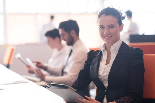 business woman on meeting usineg tablet computer, blured group of people in background at  modern bright startup office interior