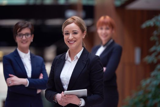 young business woman group,  team standing in modern bright office and working on tablet computer