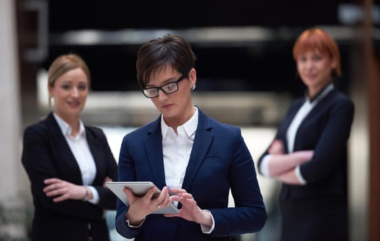 young business woman group,  team standing in modern bright office and working on tablet computer