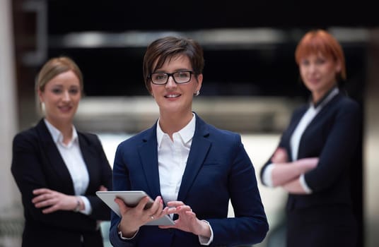 young business woman group,  team standing in modern bright office and working on tablet computer