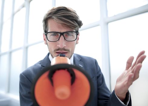 businessman screaming a megaphone and looking intently into the camera