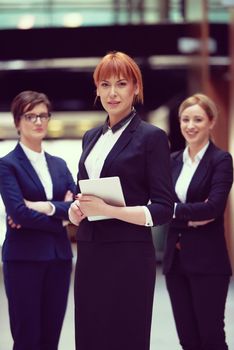 young business woman group,  team standing in modern bright office and working on tablet computer