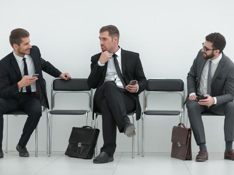 employees with smartphones sitting in the office hallway.photo with copy space