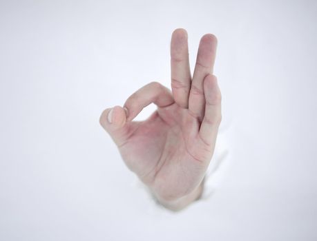 man's hand breaking through the paper wall and pointing at you .photo with copy space