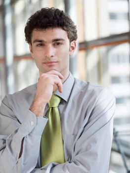 portrait of young business man at modern office  interior with big windows in background