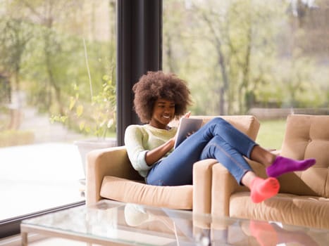 Young african american woman at home relaxing in her luxury lliving room reading a digital tablet  surf internet and work