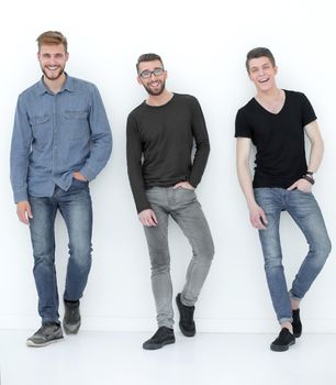 three casual men having a break and rest, standing by the wall in the studio