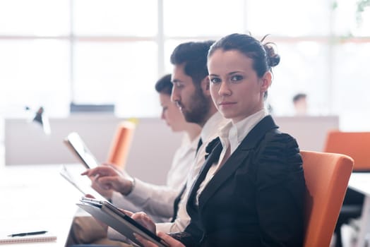 business woman on meeting usineg tablet computer, blured group of people in background at  modern bright startup office interior