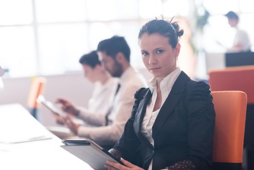 business woman on meeting usineg tablet computer, blured group of people in background at  modern bright startup office interior