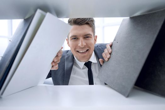 businessman in the background smiling and holding documents that stand on a shelf in a cabinet