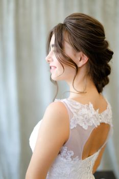 Back view of pretty brunette bride with braid hair at studio. Concepf of bridal hair do and wedding.