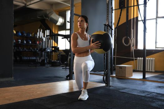 Fit and muscular woman exercising with medicine ball at gym