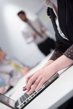 business woman hands typing on laptop  computer  on meeting, blurred people group brainstorming in background  at modern bright office interior