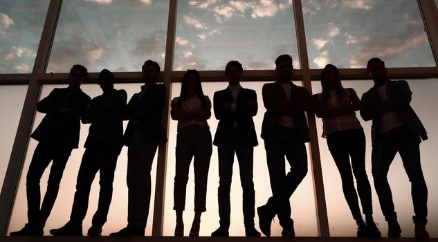 silhouette of a group of business people standing near the office window .photo with copy space