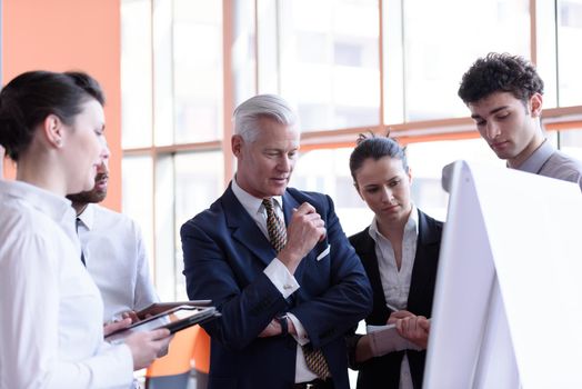 young startup businessman making presentation of project to senior investior, group of business people taking notes and make plans on white  flip board and tablet computer