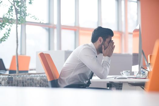 frustrated young business man working on desktop  computer at modern startup office interior