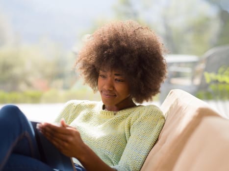 Young african american woman at home relaxing in her luxury lliving room reading a digital tablet  surf internet and work