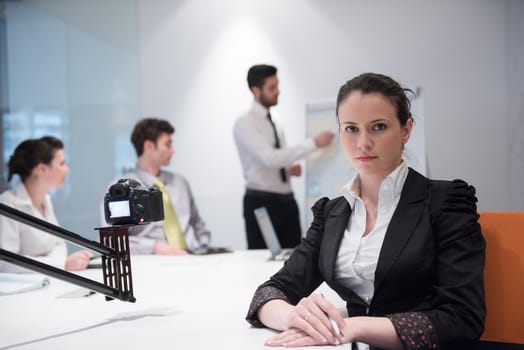 young business woman on meeting usineg laptop computer, blured group of people in background at  modern bright startup office interior taking notes on white flip board and brainstorming about plans and ideas