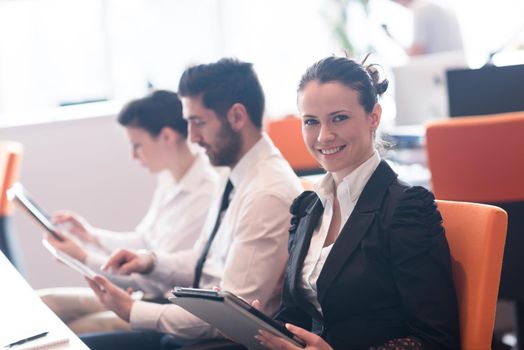 business woman on meeting usineg tablet computer, blured group of people in background at  modern bright startup office interior