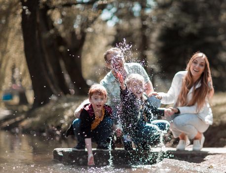 parents play with children near the lake in the city Park. the concept of family entertainment