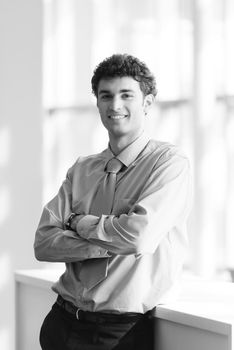 portrait of young business man with curly hair and  at modern bright office  interior with big windows in background