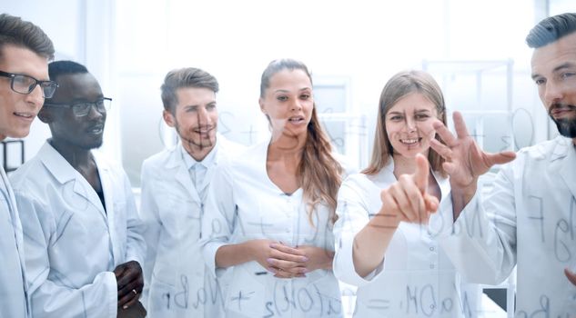 group of concentrated colleagues in white coats discussing work in laboratory