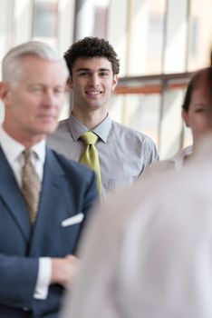 portrait of young business man with curly hair and  at modern bright office  interior with big windows in background and people group in front