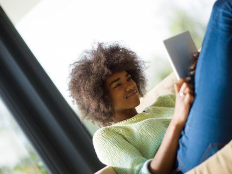 Young african american woman at home relaxing in her luxury lliving room reading a digital tablet  surf internet and work