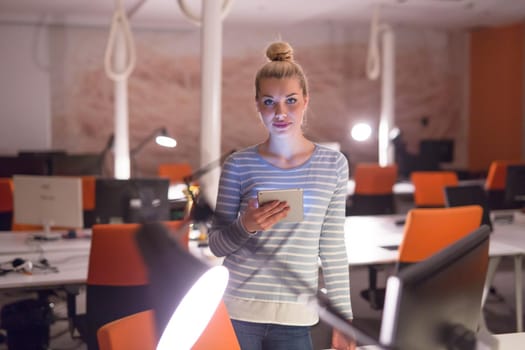 young female entrepreneur working on digital tablet in night office