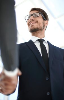 young businessman in glasses shakes hands with his colleague. view from below