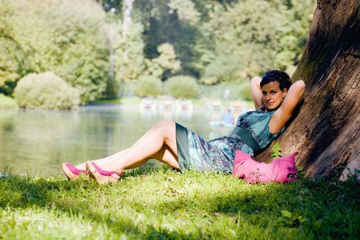 young pretty brunette woman in green park resting among grass and flowers, outside lifestyle concept