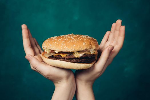 hamburger in hands close-up fast food green background. High quality photo