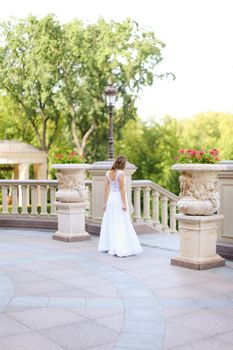 Back view of oung bride walking outside in white nice dress. Cponcept of wedding day, fiancee.