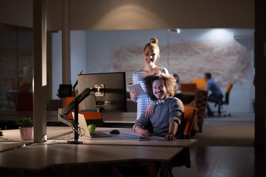 Two young designers are working on a new project in the night office using modern technology