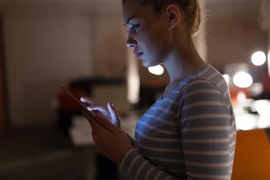 young female entrepreneur working on digital tablet in night office