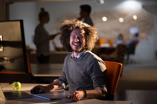 Young man working on computer at night in dark office. The designer works in the later time.