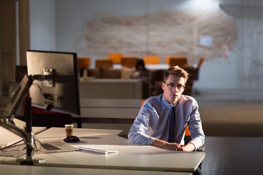 Young man working on computer at night in dark office. The designer works in the later time.